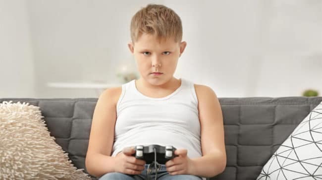 bambino sedentario mentre gioca videogiochi